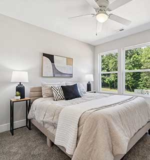 Modern bedroom with light bedding, nightstands, and abstract wall art