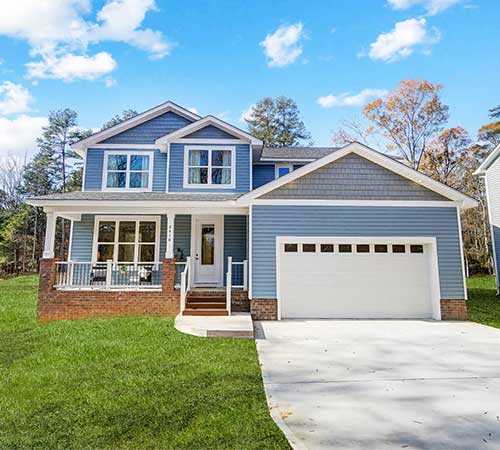 Modern two-story blue house with white trim, garage, and manicured lawn